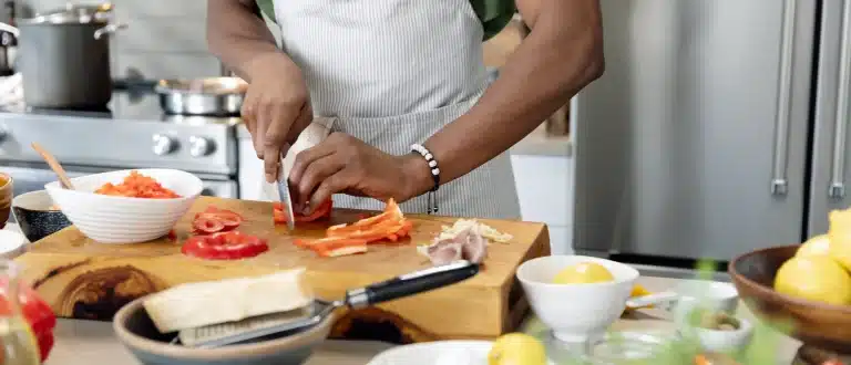 man cutting bell peppers in kitchen
