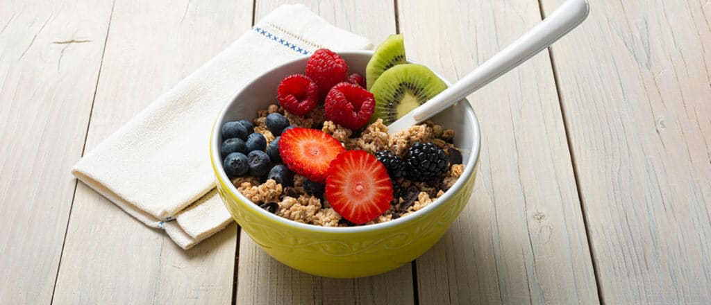 A bowl of anti aging foods including berries and kiwi