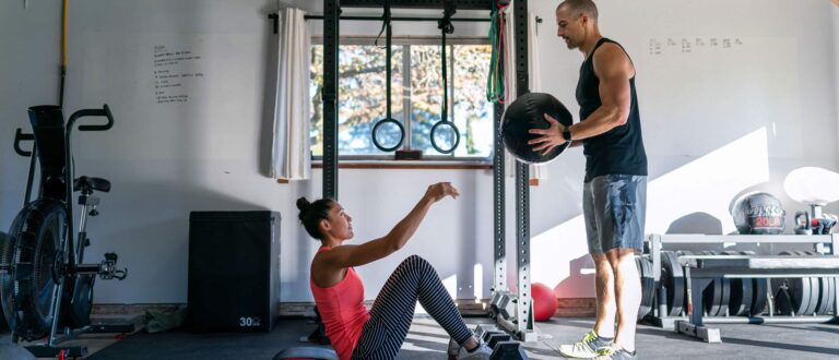 Man passing medicine ball to woman in home gym