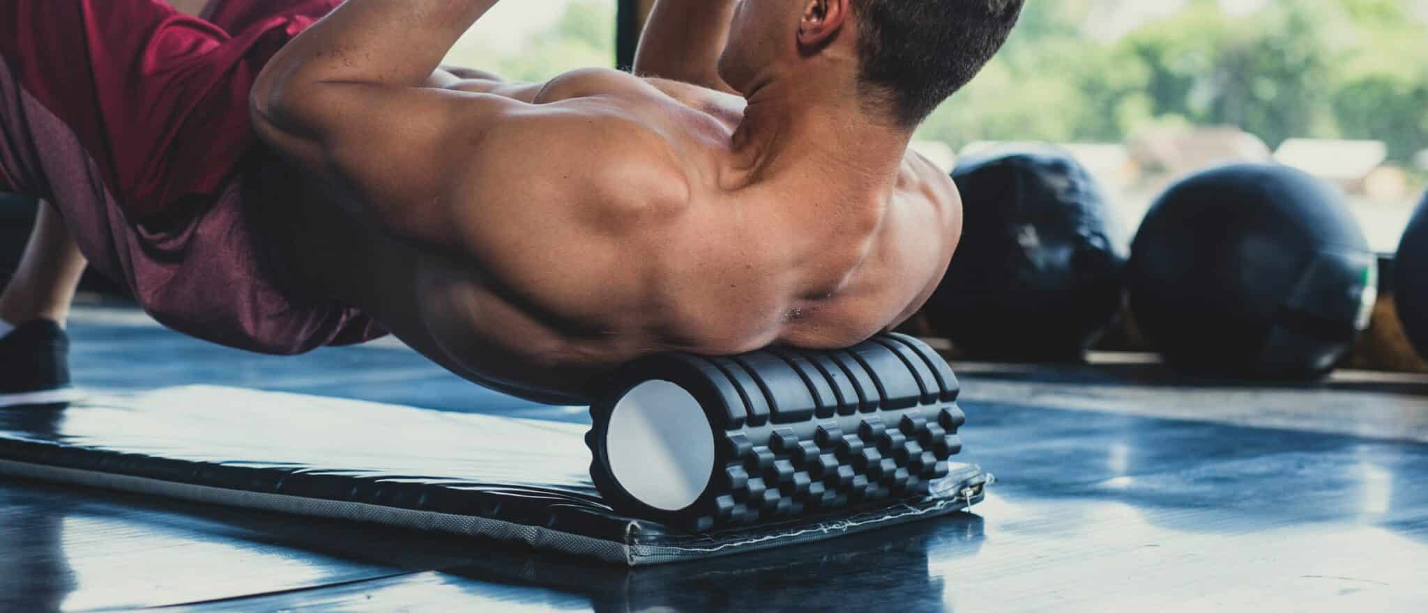 A man is propped up using a foam roller under his shoulder blades