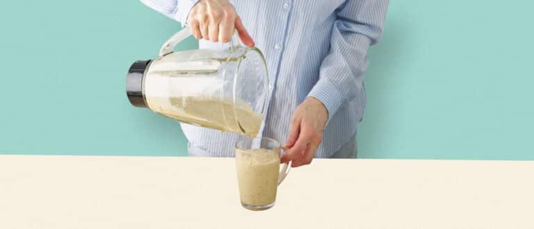 man pouring a protein drinkinto cup from blender
