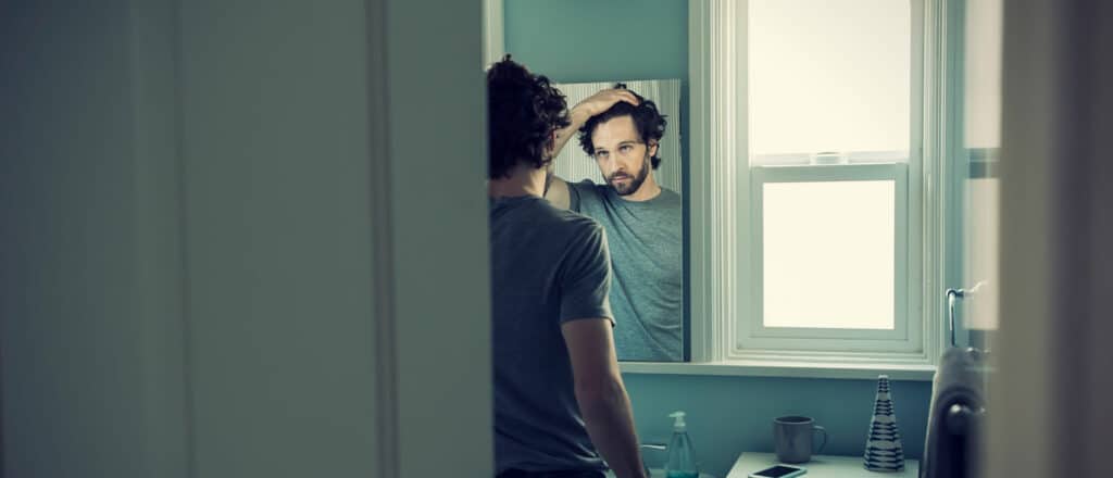 A man looks in the mirror for symptoms of low testosterone