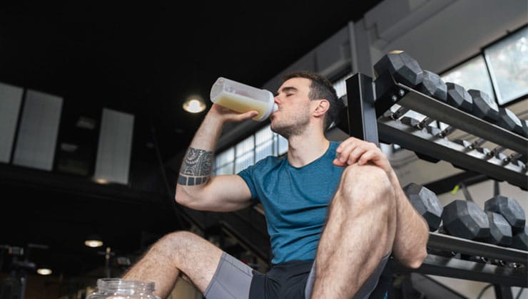 a guy drinks a protein shake after a workout
