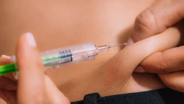 Man pinching skin and getting ready to inject syringe