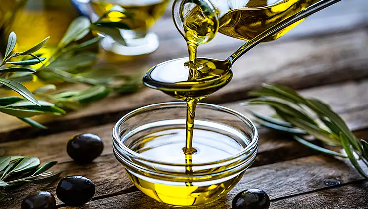 Pouring extra virgin olive oil in a glass bowl - stock photo
