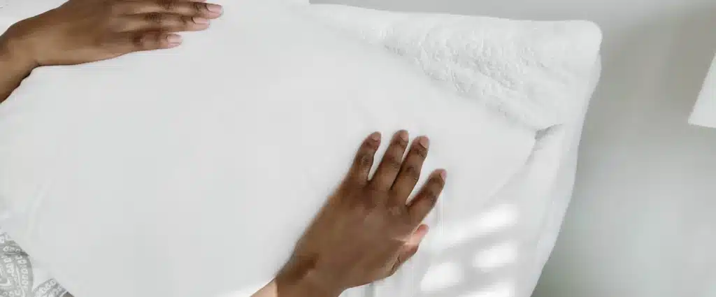 overhead shot of person holding a pillow over their eyes in bed in the morning