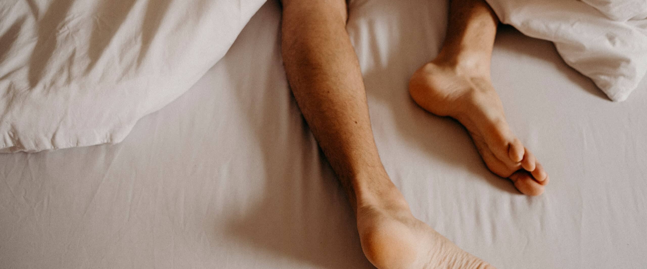 a close up of man's feet out of the bottom of a quilt
