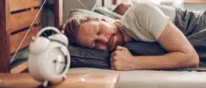man sleeping next to alarm clock