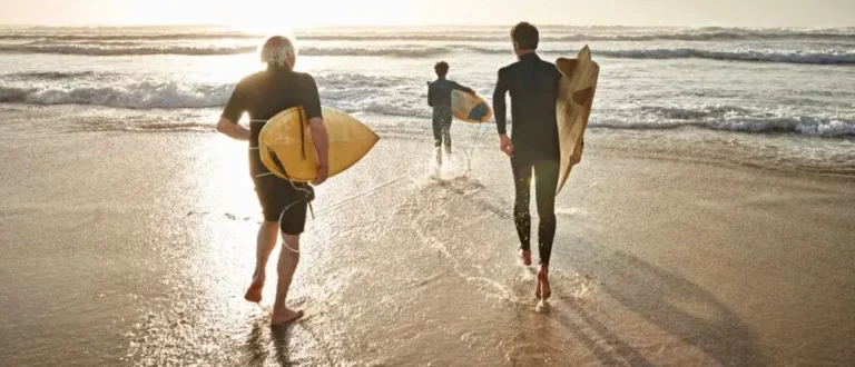 two men carrying their surfboards into the ocean