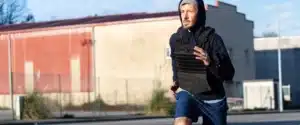 A man runs outside while wearing a weighted vest