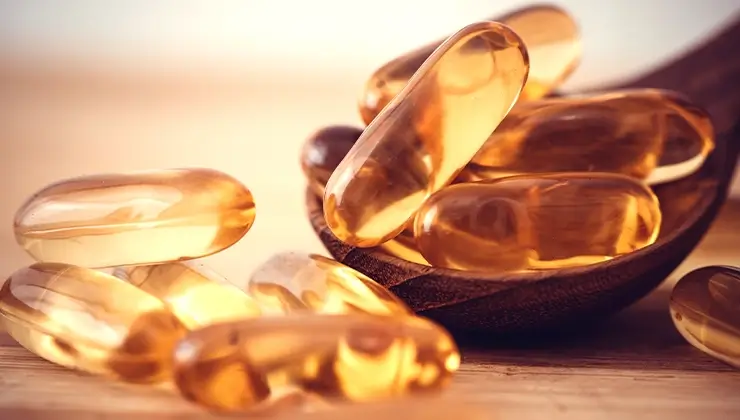 vitamin D capsules on wooden spoon