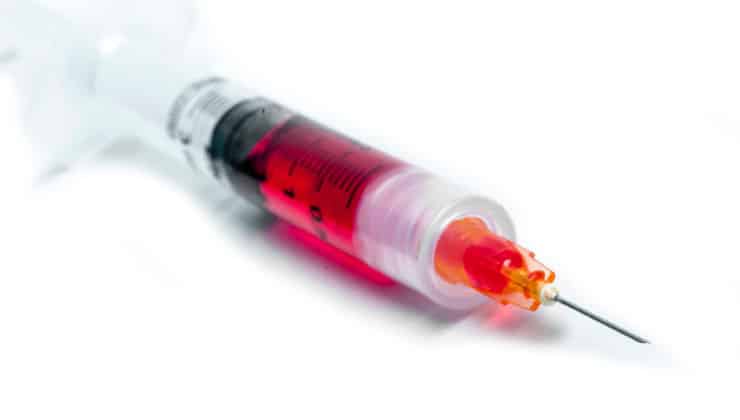 syringe with red liquid on white counter