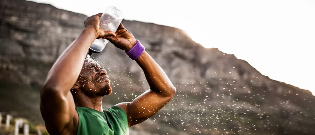 A sweaty athlete splashes himself with water