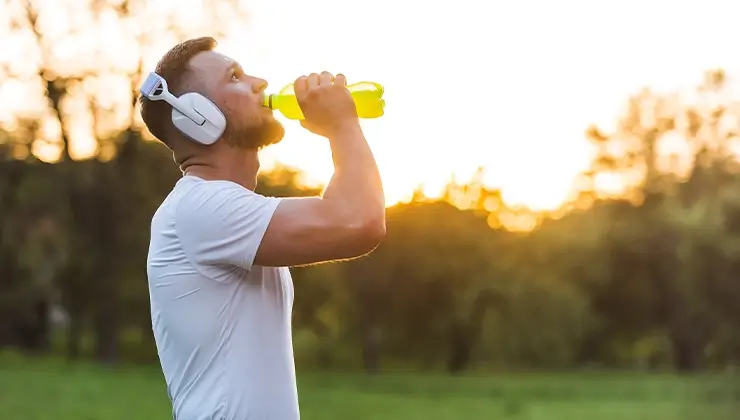 man drinking electrolyte drink during workout