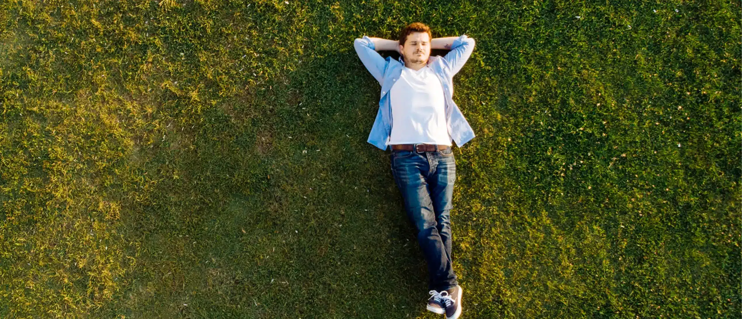 a man lays in the grass, free from anxiety