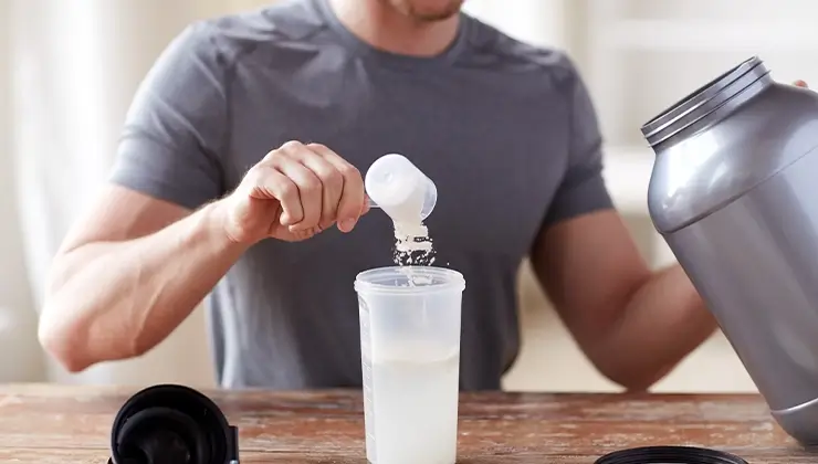 man pouring protein powder into shaker bottle