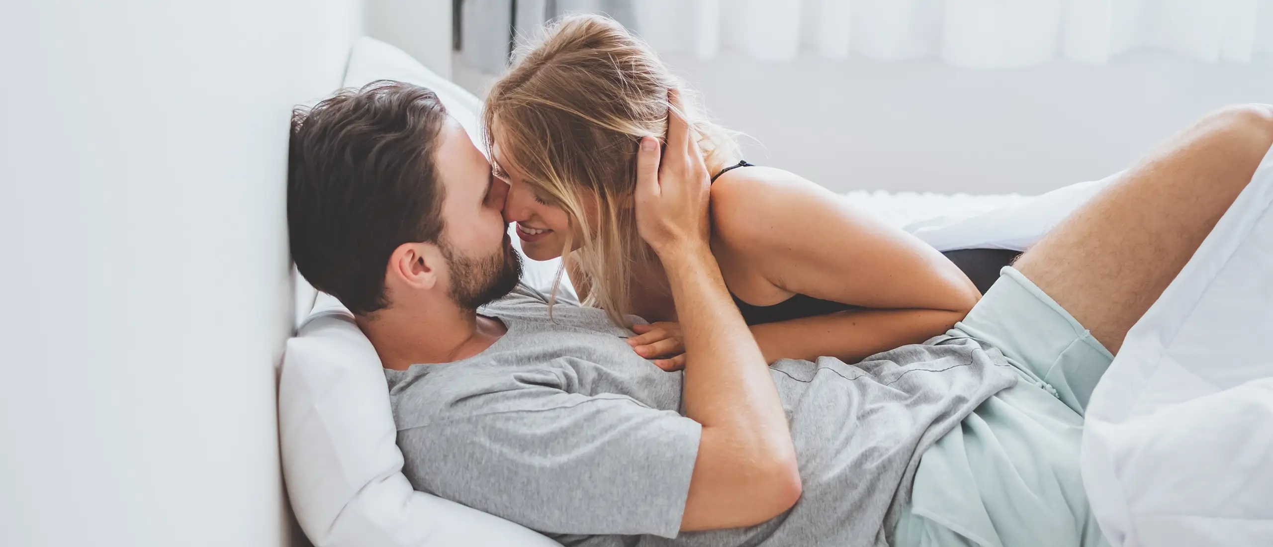 man and woman kissing in bed