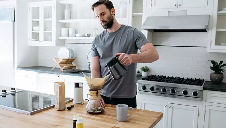 Man pouring making coffee in kitchen