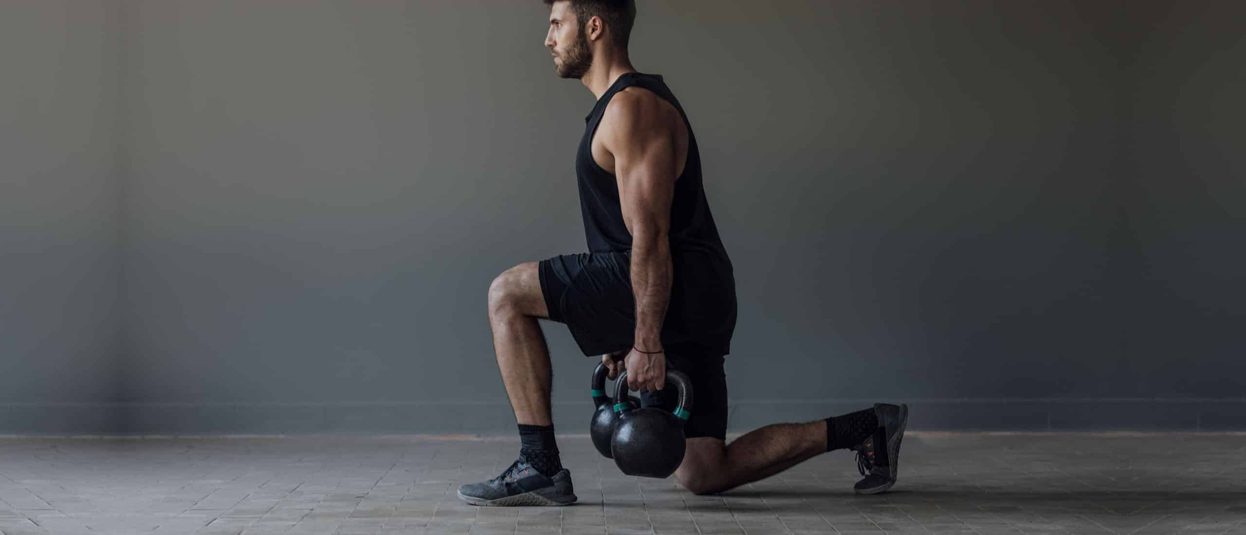 Man doing lunges with kettlebells