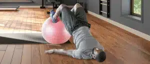 Man doing hip thrust glute bridge with feet on a yoga ball