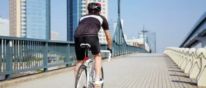 Man cycling over a city bridge.
