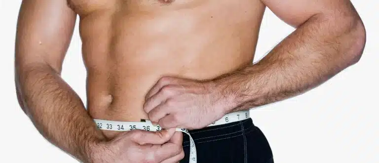 a shirtless man measures his waist