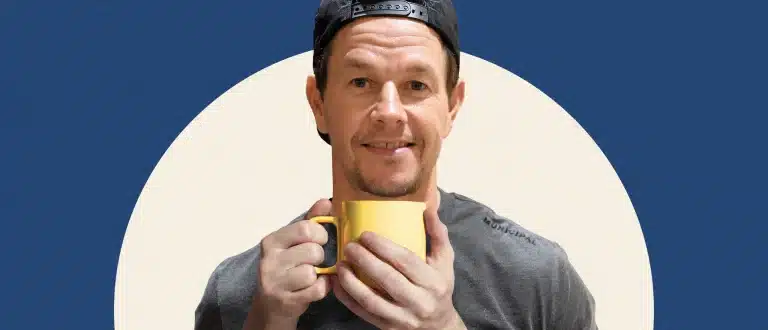 Mark Wahlberg holding cup of coffee on beige and blue background