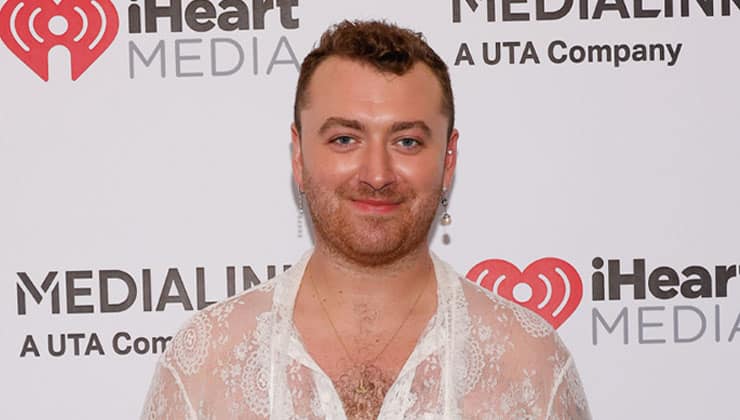 Sam Smith standing in front of backdrop