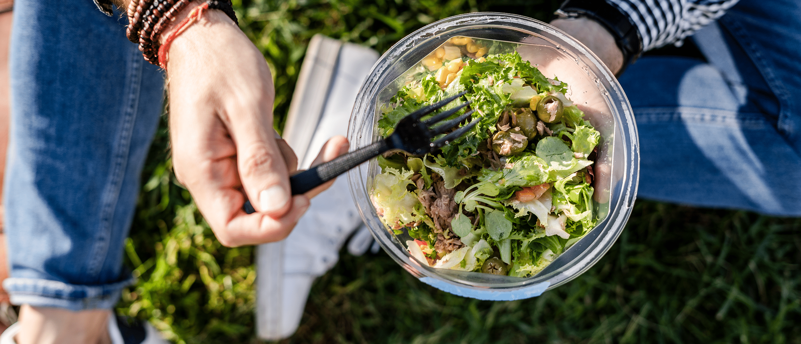 man eating a salad in the grass