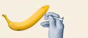 A gloved hand injects a banana with a syringe