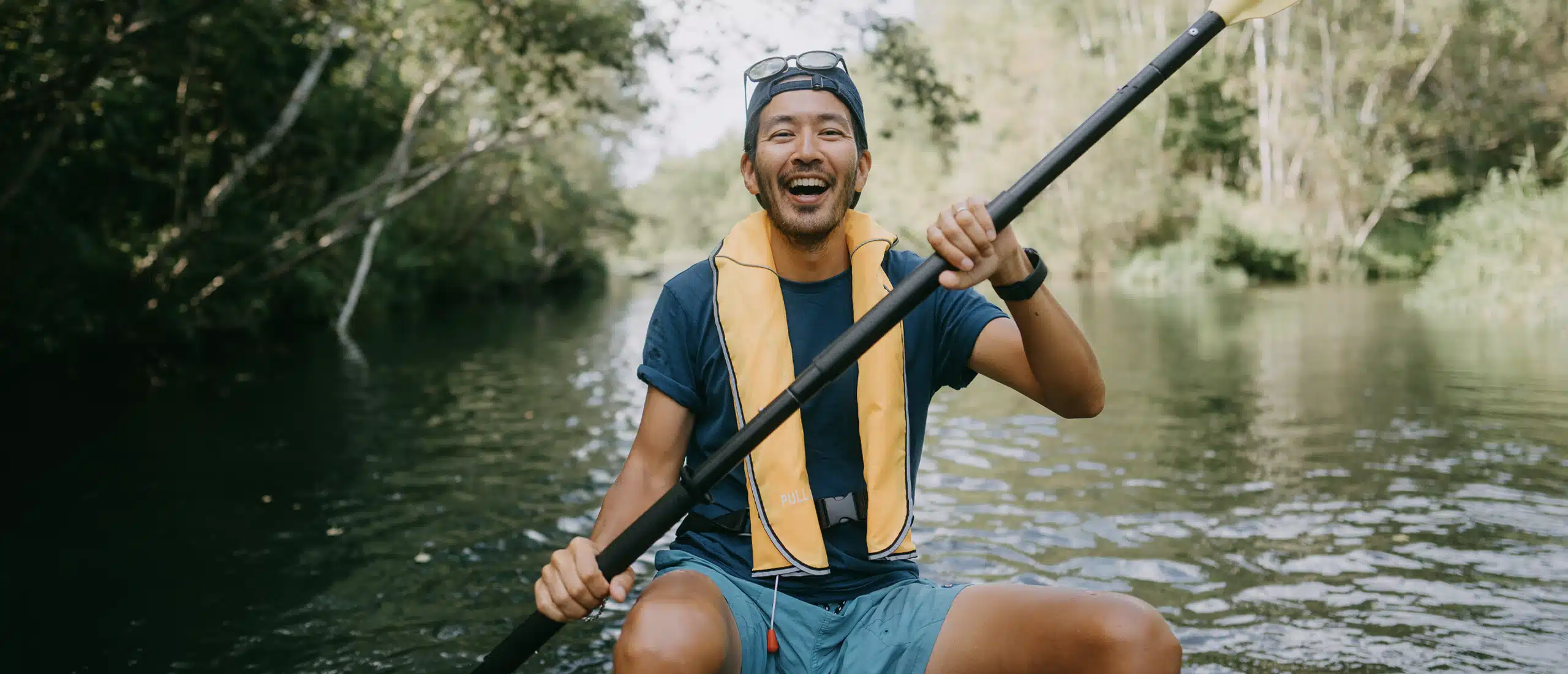 Man smiles while paddling a kayak