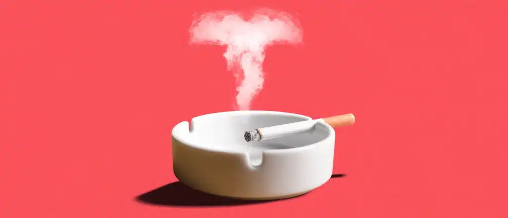 a cigarette in an ash tray with smoke rising in the shape of a T