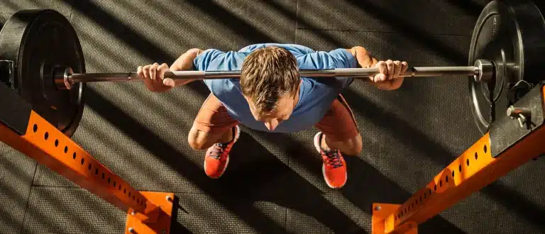 overhead view of man back squatting with a bar loaded with plates.
