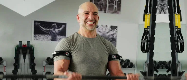 Peter Attia doing blood flow restriction bicep curls, showing off his sweet muscle pump.