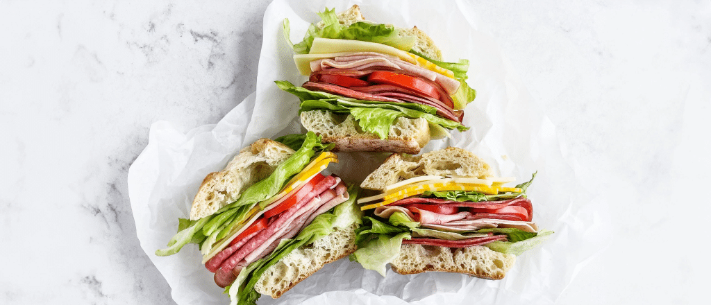 Sandwiches loaded up with deli meat, veggies, cheese, and lettuce.