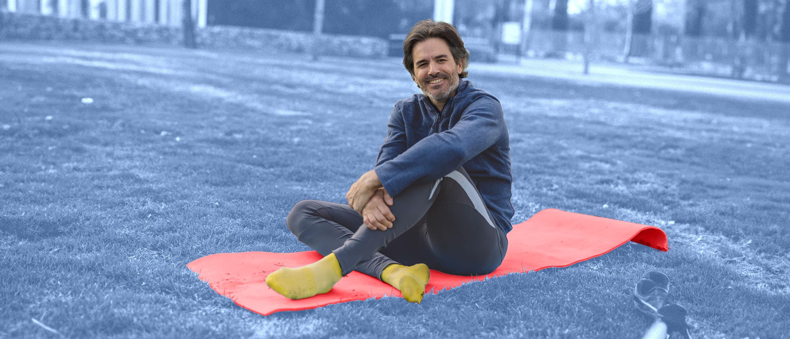 Man sitting on red mat with blue background