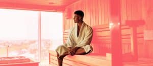 man wearing robe sitting in sauna