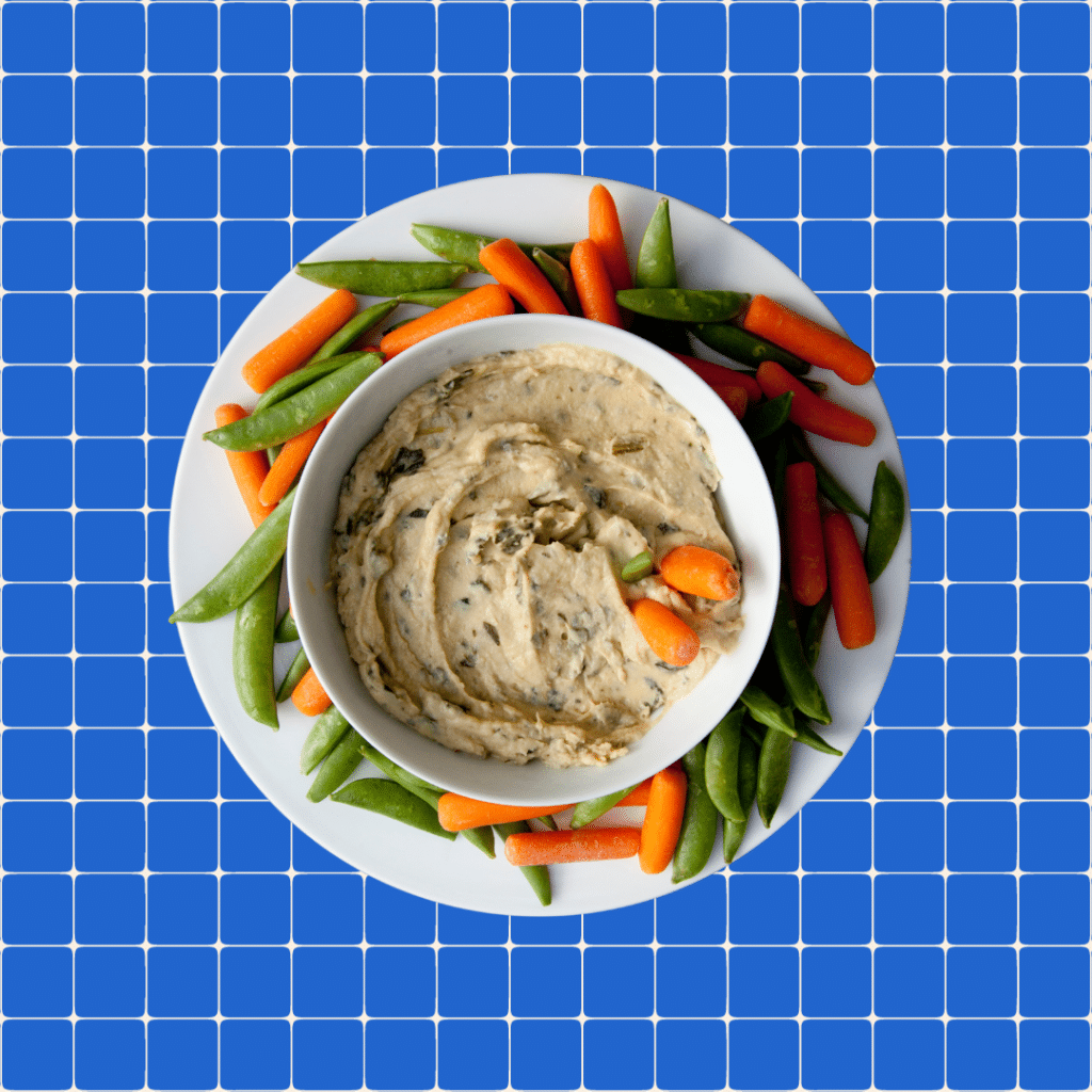 hummus and veggies on blue grid background