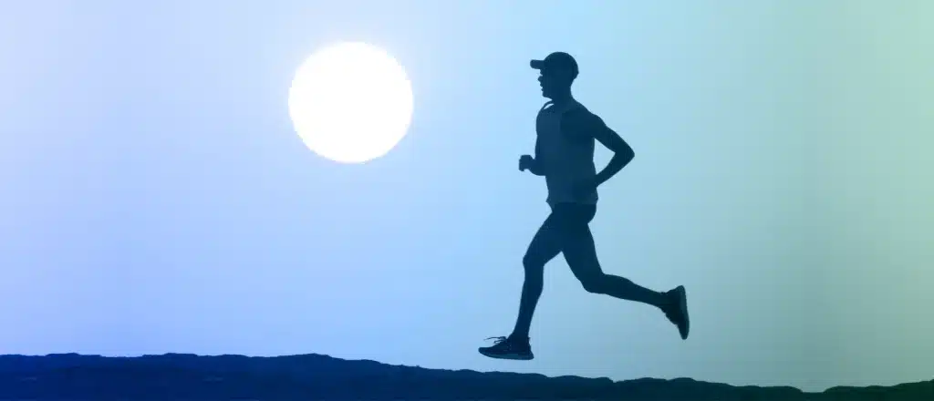 man running alongside mountains, the moon, and a dark blue and green sky.