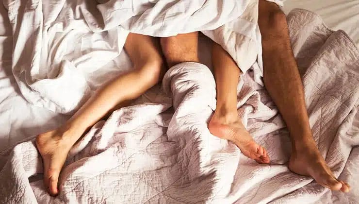 legs of man and woman in bed cuddling