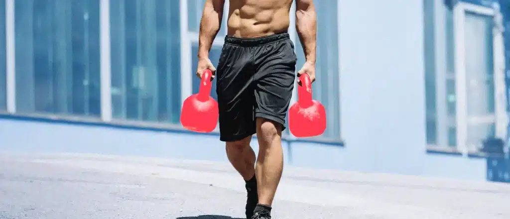 Man carrying two heavy kettlebells, one in each hand.
