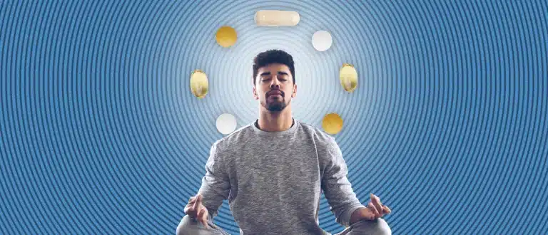 Man meditating surrounded by supplements