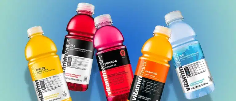 different flavors of vitamin water bottles on a blue background.