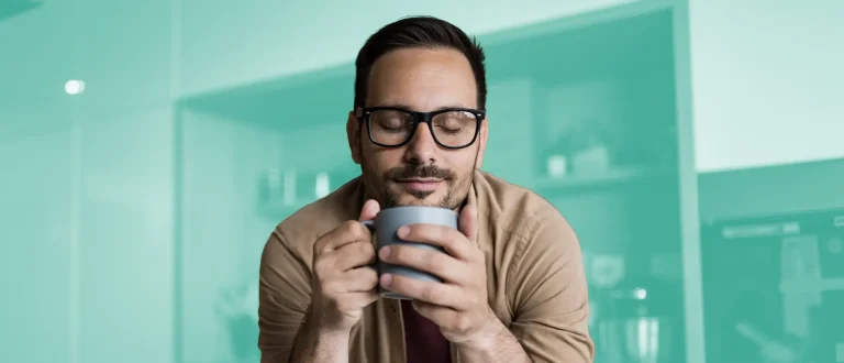 man happily sipping from a warm mug.