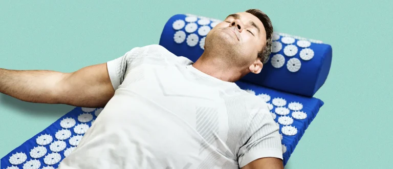 man lays on his back on a acupressure mat