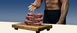 Man reaching for a giant stack of steak.