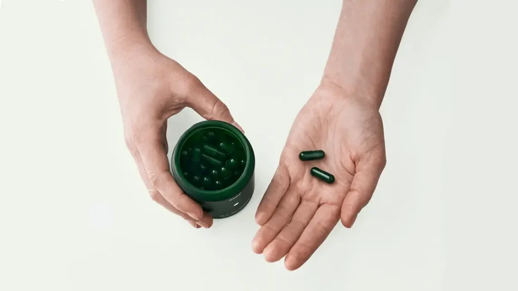 hands holding seed synbiotic jar and pills