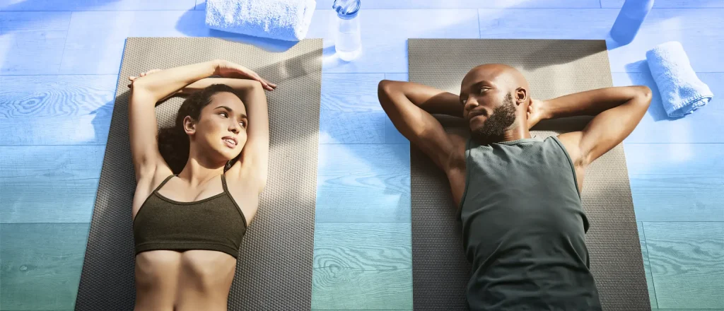 Woman and man resting on yoga mats looking at each other
